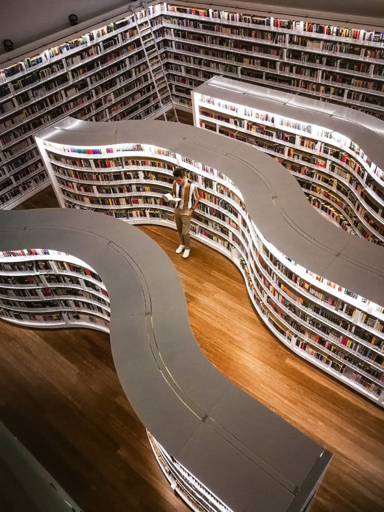 man standing inside library while reading book